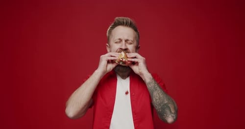 Blond Man Enjoys Eating Large Burger Close-Up