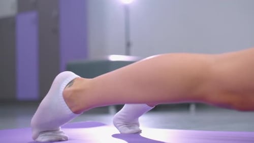 Leg View of Person in White Socks Stretching on Purple Mat with Light Reflection