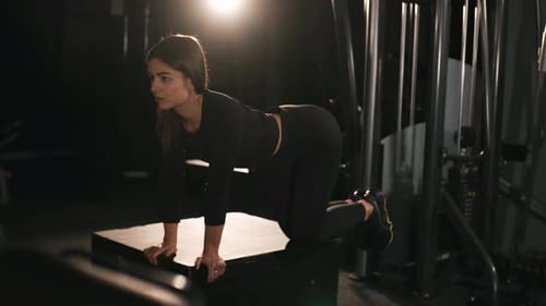 Woman Performs Glute Exercise on Platform in Gym