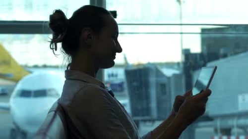 Silhouette of Woman Watching Movie on Tablet Sitting in Lobby at Airport Adult