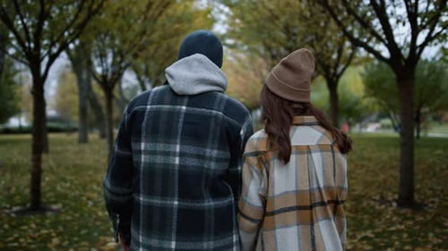 Rückansicht eines liebenden Paares, das tagsüber im Autumn Park spaziert. Nahaufnahme