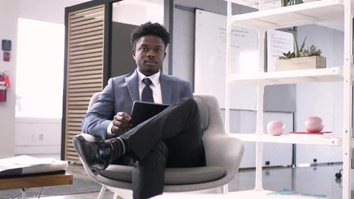 Confident young african american businessman working with digital tablet in office
