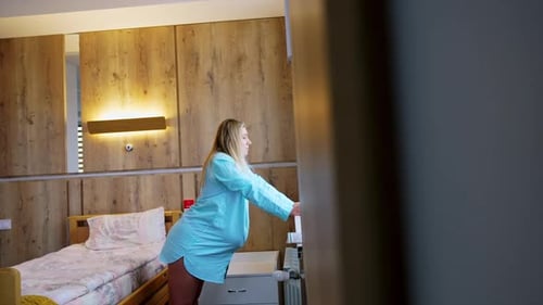 La mujer rubia se apoya en el alféizar de la ventana para sentir alivio de las contracciones.