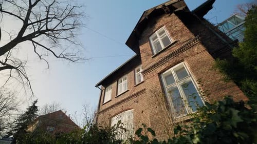 Das alte Backsteinhaus steht hoch vor klarem blauem Himmel aus einem niedrigen Winkel