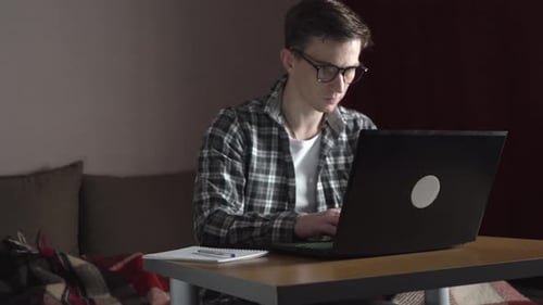 Young Adult Taking Notes and Using Laptop