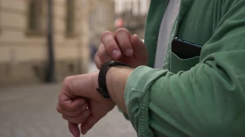 Man check time on smartwatch on city street