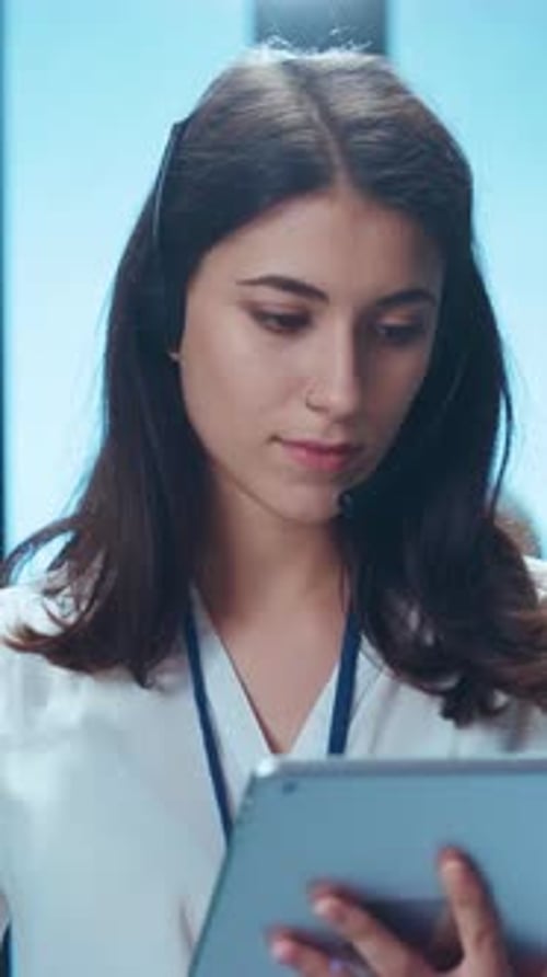 A Focused Call Center Agent is Working Diligently with a Tablet in a Modern Office Environment