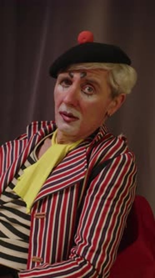 Clown with Makeup and Striped Jacket Sits Still