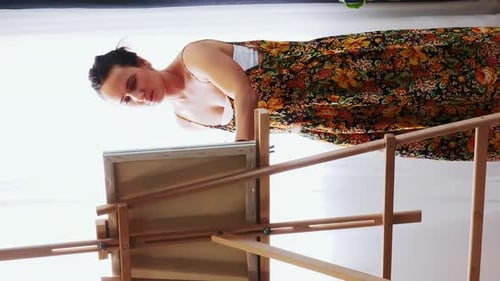 Girl artist in art home studio standing behind an easel and painting on canvas