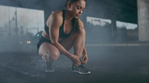 Beautiful Confident Fitness Girl in Black Athletic Top and Shorts Ties Shoelaces and Starts Running