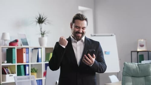 Office Worker Making Winner Gesture with Phone Indoor