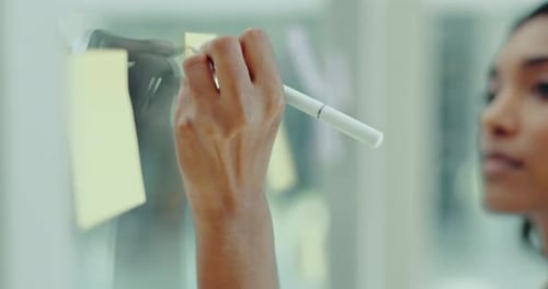 Young Adult Writing on Glass Whiteboard