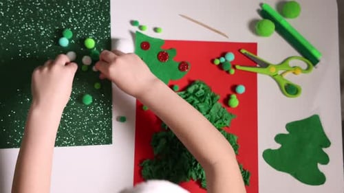 Little boy making Christmas postcard at white table, top view. Child handmade craft