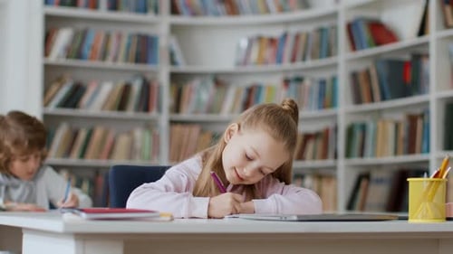Young Girl Writing at Desk in Library