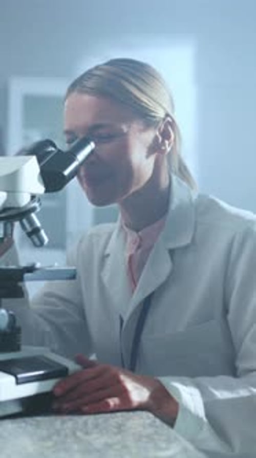 Woman Works with Microscope in Bright Laboratory