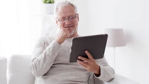 Senior man using tablet on couch at home