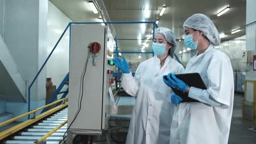Les superviseurs féminins examinent le contrôle de la qualité sur le convoyeur dans la fabrication.