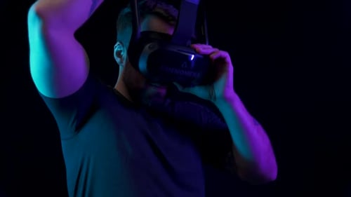 Man Putting on Virtual Reality Headset in Dark Room