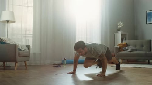Athletic Fit Man in T-shirt and Shorts is Doing Mountain Climber Exercises While Using a Stopwatch