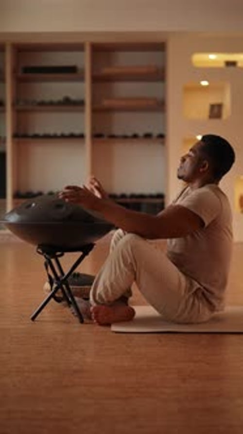 Vertical Shot of African Man Playing Traditional Ethnic Music Using Glucophone Sitting on Floor in