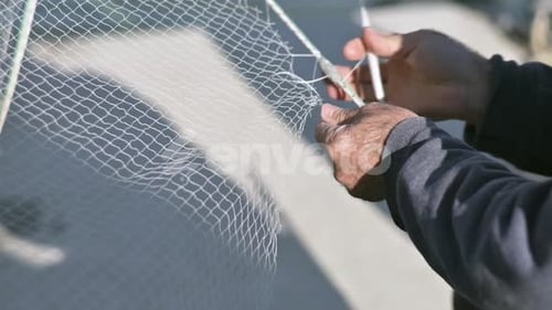 A close-up shot of a fisherman fixing his net, representing traditional fishing culture and manual c