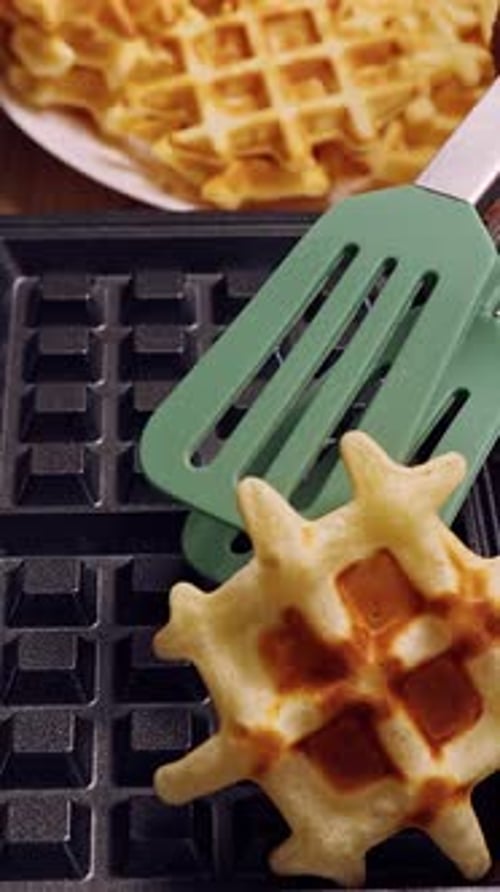 Vertical video. Removing Golden Brown Waffle From Iron With Spatula, Motion Blur Showing Fast