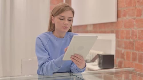 Woman Uses Tablet Indoors at Glass Table