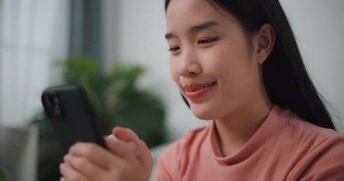 Smiling Young Woman Using Smartphone Indoors