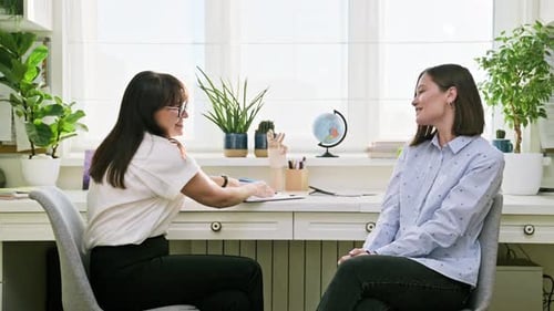 Smiling Psychologist and Young Woman Patient Shaking Hands in Office