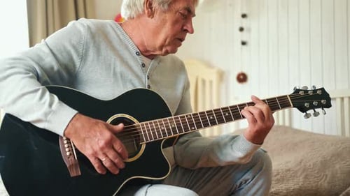 Senior Man Playing Acoustic Guitar in Bedroom