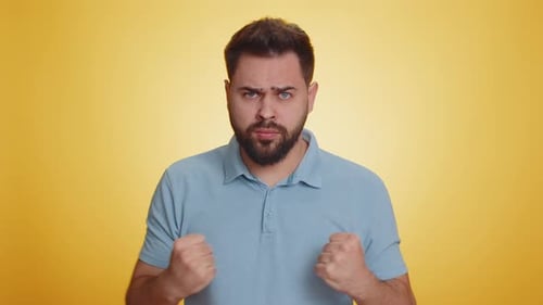Man Clenches Fists Angrily on Yellow Background