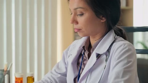 Doctor Taking Notes at Desk in Bright Office