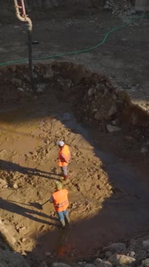 Vídeo vertical: equipo pesado y trabajadores que construyen estructuras en un sitio de construcción