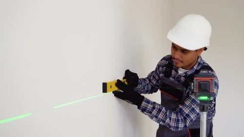 Indian Worker Measuring Walls with Laser Level Tool