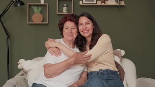 Smiling Women Embracing on Sofa Indoors