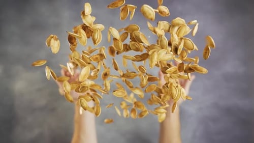 Hands Toss Toasted Pumpkin Seeds in the Air