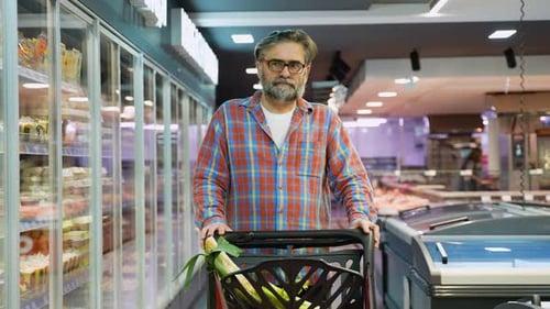 Senior Man Pushing Shopping Cart in Grocery Store Aisle