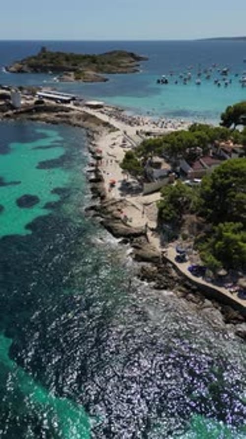Playa illetas with clear turquoise waters and sunbathers on the beach, mallorca, spain, aerial view