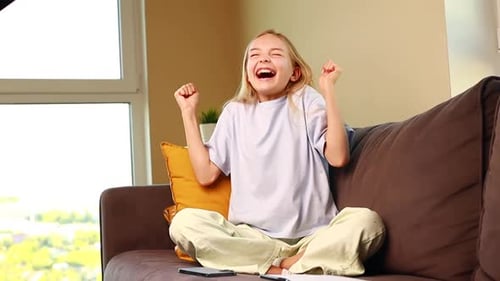 Happy Girl Cheering on Couch in Living Room