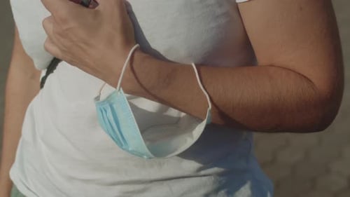 Man Wearing Face Mask Around Hand Wrist - close up