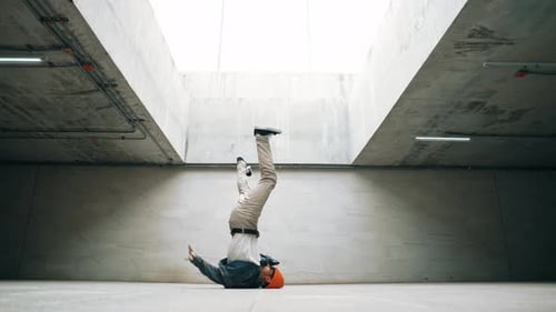 Stylish happy hipster perform break dance or foot step in building. Sprightly.
