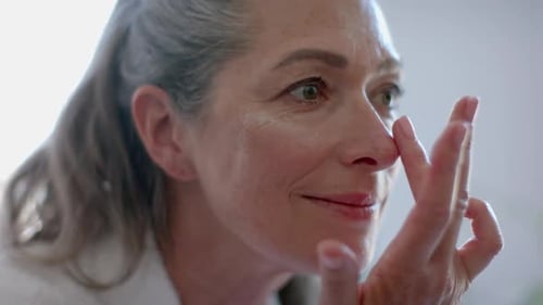 Senior Woman Applying Lotion to Her Face