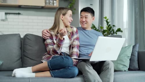 Happy young married couple shopping online choosing a product in online store together on laptop