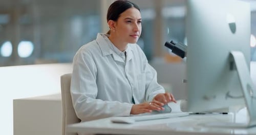 Young Woman Using Microscope at Computer Desk