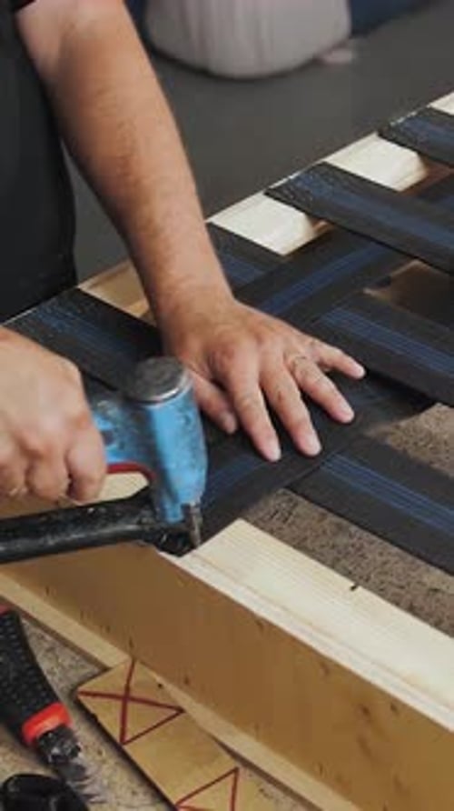 Vídeo vertical El proceso de fabricación de muebles tapizados Un trabajador hace un sofá Primer plano de un hombre