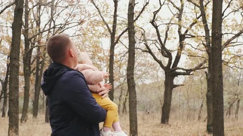 Happy Family with Little Daughter Walking in an Autumn Park in Forest