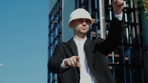 Engineer Points at Digital Screen Near Building