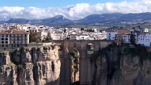 Ronda Spain showing Puente Nuevo bridge, cliffs and white houses under cloudy sky