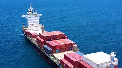 Aerial footage of a container ship approaching a commercial port.