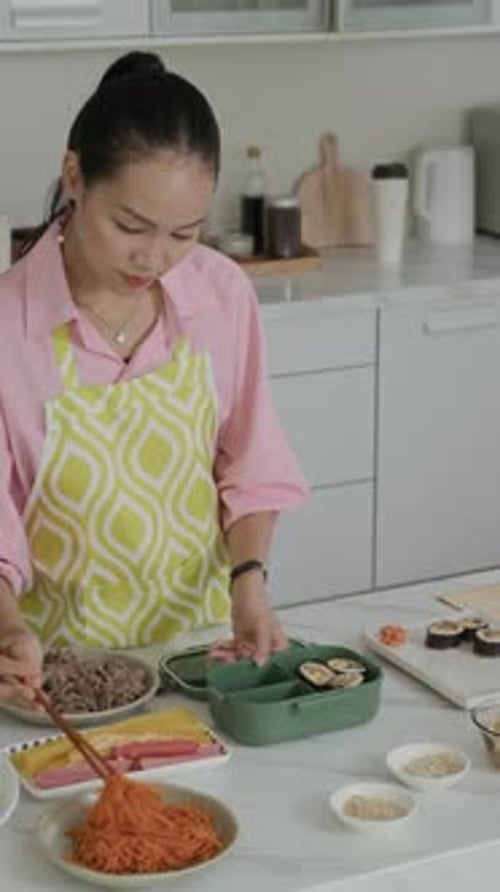 Vertical of Housewife Putting Sushi in Food Container at Kitchen